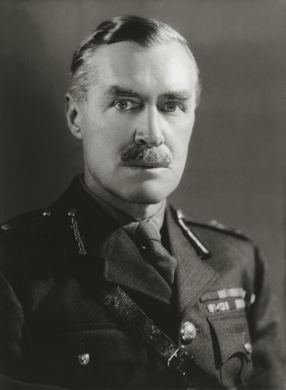 A black-and-white picture of a middle-aged British officer with a mustache looking directly at the camera. Rank insignia are visible on his lapels and chest.